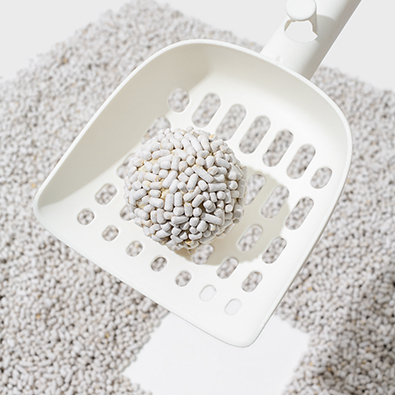 Scooping clumped cat litter with a litter scoop.